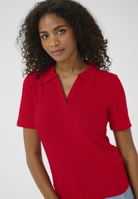 Rot gestreiftes Poloshirt mit kurzen Ärmeln und V-Ausschnitt, das über eine glatte Textur und eine figurbetonte Silhouette verfügt.