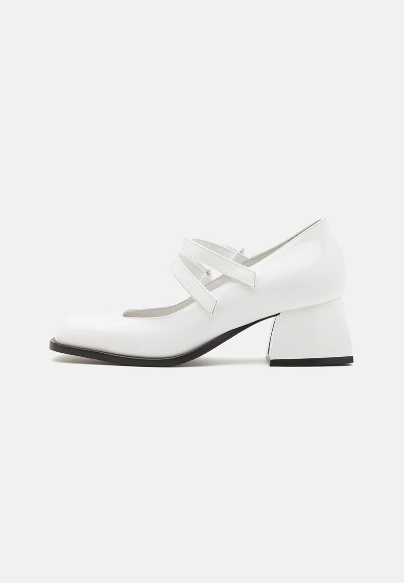 Białe lakierowane buty Mary Jane z dwoma krzyżującymi się paseczkami, kwadratowym noskiem i bloku, z błyszczącym wykończeniem i czarną podeszwą.