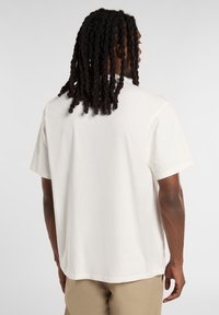 Camiseta de algodón blanca con un corte relajado, mangas cortas y un escote redondeado, que presenta una textura suave y detalles de costura mínimos.