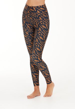 Leggings navy avec un motif de rayures de tigre marron, dotés d'une taille haute et d'un tissu lisse et extensible. Design ajusté avec une longueur au niveau des chevilles.