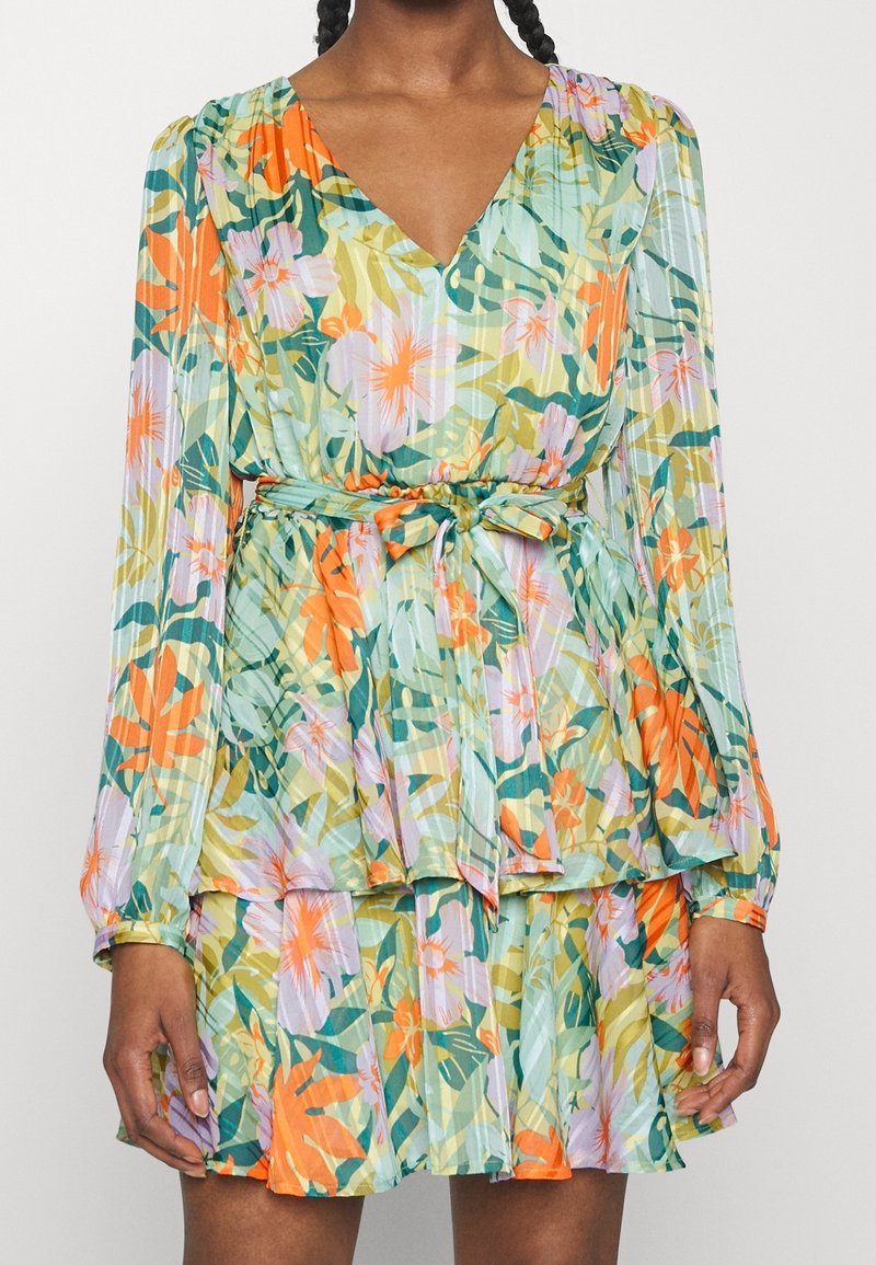 Blommig klänning med v-ringning, långa ärmar, elastisk midja med knytning och lager-skirt. De dominerande färgerna är grön, orange och lila.