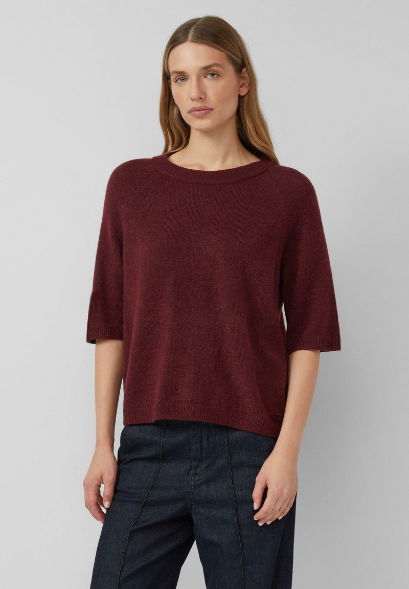 Pull en tricot bordeaux avec un large décolleté rond, des manches raglan courtes, et une coupe ample, avec une finition douce et texturée.