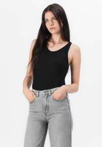 Zwart geribbeld bodysuit met een ronde halslijn, gecombineerd met lichtgrijze high-waisted denim jeans met voorzakken en een knoopsluiting.