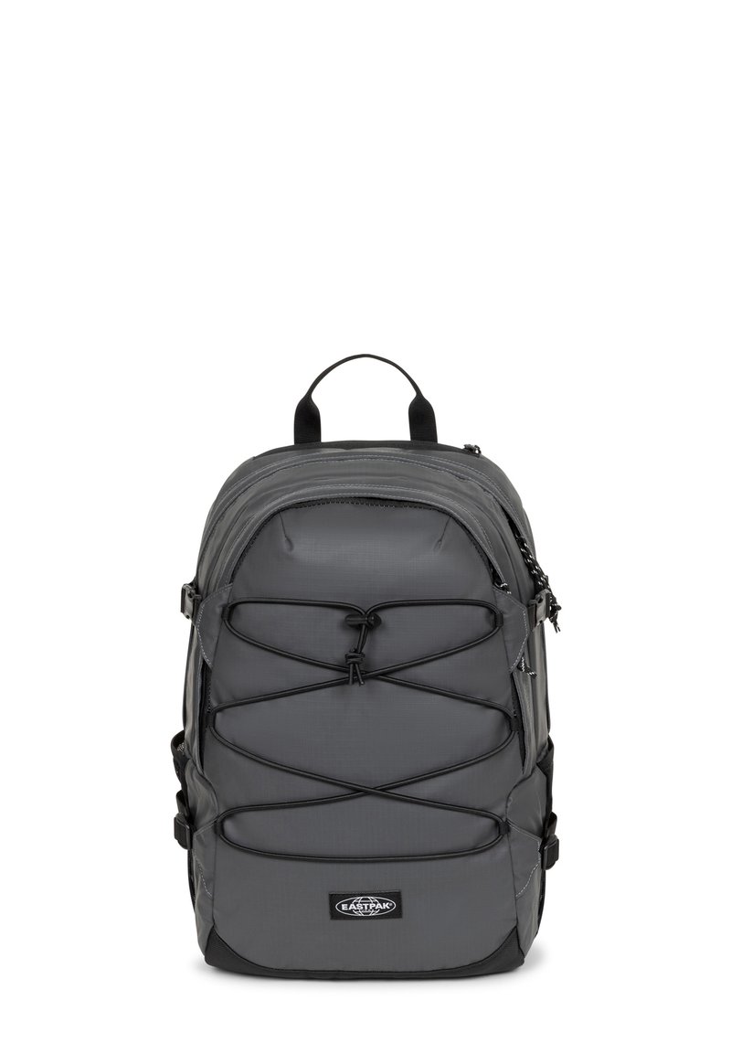 Zaino grigio realizzato in un tessuto robusto, con un design a corda bungee nella parte anteriore, manico superiore e spallacci regolabili per comfort e utilità.