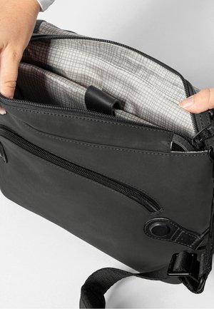 Borsa a tracolla nera con due scomparti con zip, caratterizzata da un rivestimento a quadri e una tracolla rimovibile. Materiale resistente con texture liscia.