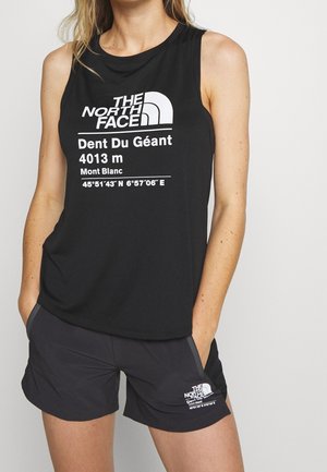 Frau trägt ein schwarzes ärmelloses Oberteil und Shorts mit weißem "The North Face"-Logo und den Koordinaten des Dent Du Géant-Berges darauf gedruckt.
