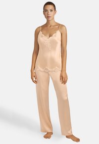 Ensemble de pyjama en satin pêche comprenant un débardeur à dentelle et des bretelles réglables, accompagné d'un pantalon assorti au toucher doux et à la coupe ample.