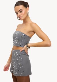 Ensemble gris en deux pièces comprenant un haut court bustier sans bretelles et un short taille haute, orné de diverses embellissements et accents brillants.