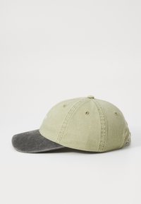 Groene katoenen pet met een donkergrijze klep, voorzien van zes ventilatiegaten, een gestikte bovenknop en een logo label aan de zijkant.