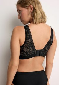 Bralet din dantelă neagră, cu design floral și panouri din plasă, bretele late și închidere cu cârlig și ochi în spate. Benzi din material neted în partea de jos.