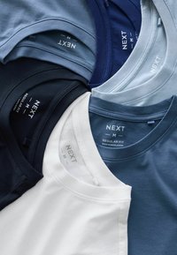 Set med fem T-shirts med rund hals i olika blå nyanser, plus vit. Mjuk bomullsmaterial med synliga varumärkesskyltar och etiketter för regular fit.