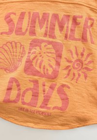 Orange Baumwollstoff mit fettem pinkem Text, der "SOMMERTAGE" liest, sowie Grafiken von Muscheln, Blättern und der Sonne. Texturierte, weiche Oberfläche.