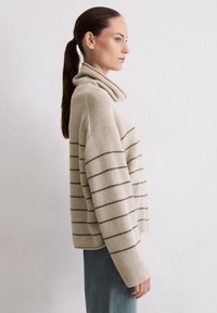 Beżowy sweter dziany z kapturem, z ciemnozielonymi poziomymi paskami. Luźny krój i ściągacze, miękka faktura.