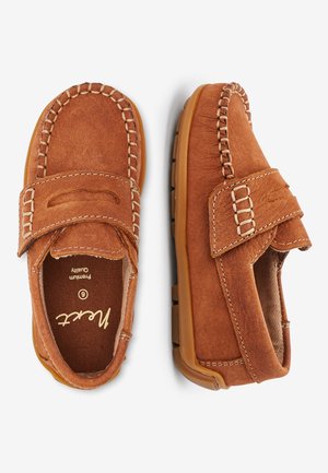 Pantofi din suede maro cu o formă rotundă, cusături contrastante și o curea cu prindere tip arici. Interior moale și talpă din cauciuc.