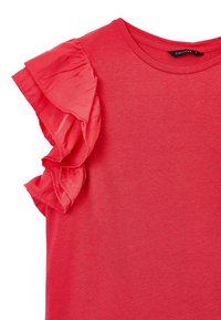 Maglietta rossa con scollo rotondo e un'accattivante accentuazione in tessuto leggero e trasparente sulla spalla sinistra. Materiale in cotone liscio e leggero.