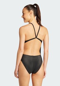 Čierny plavkový set s textúrovaným dizajnom, tenkými nastaviteľnými ramienkami a vysokým strihom. Zadný pohľad zobrazuje minimálne krytie.