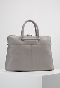 Grå læder totebag med to rundede håndtag, en lynlåslukning i toppen og et sømløst design med diskrete syninger og tekstureret overflade.