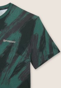 Camiseta de manga corta verde y negra con patrón abstracto, con cuello redondo y logo "FREDDY" en el pecho.