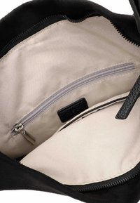Black suede handbag interior featuring a beige lining, a zippered pocket, and a small leather label. Smooth texture with contrasting colors.
