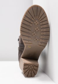 Botte cheville en suède marron avec une semelle en caoutchouc texturé, dotée d'un talon bloc et d'une fermeture éclair sur le côté. Taille 37 marquée sur la semelle.