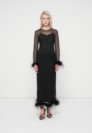 Robe noire à manches longues en matériau transparent, silhouette ajustée, avec des accents de plumes aux poignets et à l'ourlet. Présente un décolleté en V et des manches transparentes.