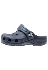 Zoccoli blu navy con un design perforato e una suola testurizzata. Presenta un cinturino regolabile e un logo circolare sul lato.