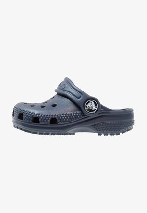 Marineblaue Clogs mit einem durchbrochenen Design und einer strukturierten Sohle. Verfügt über einen verstellbaren Riemen und ein rundes Logo an der Seite.