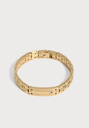 Bracelet à maillons en métal ton or avec logo "Hilfiger" gravé et petit emblème de drapeau rouge, blanc et bleu sur la plaque avant.