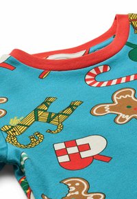 Cotton pajama shirt featuring a turquoise background with red trim. Pattern includes gingerbread cookies, candy canes, and a straw goat.