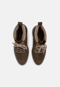 Braune Wildleder-Ankle Boots mit cremefarbenen Schnürsenkeln und einem gemusterten Strickkragen. Mit goldfarbenen Beschlägen und weißen Nähten entlang der Sohle.