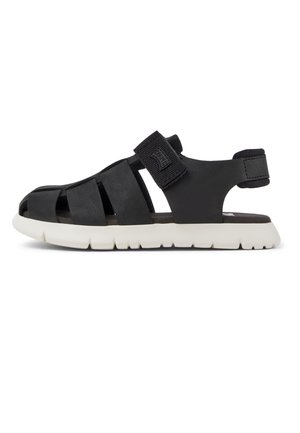 Sort lukket sandal med justerbar rem over foden og hælen, med hvid tekstureret sål.