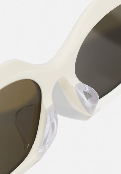 Sunglasses with a cream-colored frame, dark lenses, and unique marbled accents on the sides, showcasing a sleek, rounded design.
