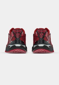 Pair of red and black athletic shoes shown from the back, featuring mesh and synthetic overlays with thick, textured soles.