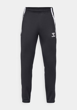 Pantalon de sport noir slim avec des bandes blanches sur les côtés et une taille élastique, avec un petit logo blanc Hummel sur la jambe avant droite.