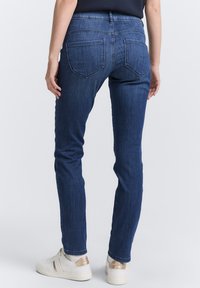 Mörkblå denimjeans med slim fit, med två bakfickor. Matchas med vita sneakers och en svart topp. Slät textur.