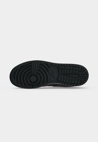 Μαύρη σόλα αθλητικού παπουτσιού Nike με κυκλικά και γραμμικά μοτίβα πέλματος και το λογότυπο Nike στο κέντρο πάνω σε απλό λευκό φόντο.