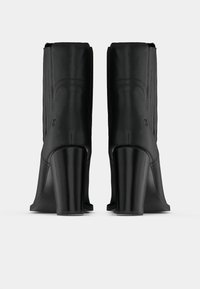 Melnas potītes zābakus ar gludu ādas apdari, augstiem blokšāvieniem un smalkām vertikālām šuvēm uz stumbra. Vienkāršs, elegants dizains.