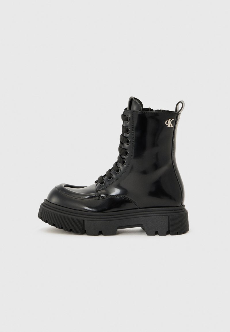 Bottines en cuir verni noir à lacets avec une semelle épaisse, dotées d'un accent logo et d'un soutien renforcé à la cheville.