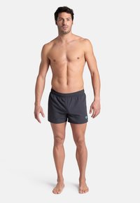 Pantaloni da bagno grigio scuro con elastico in vita, caratterizzati da un piccolo logo turchese sul lato, progettati per uno stile aderente ma comodo.