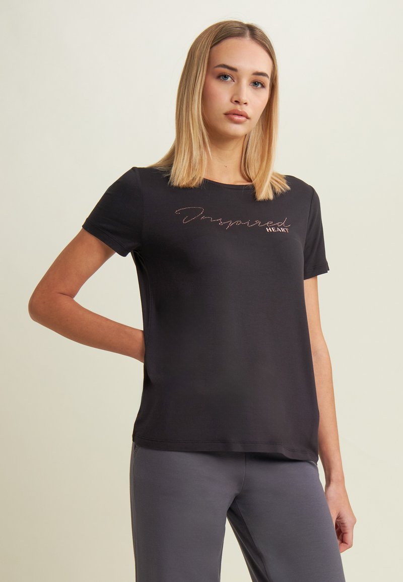 T-shirt nera a maniche corte in tessuto morbido con testo "Inspired Heart" ricamato in filato metallico. Taglio semplice e rilassato con scollatura a girocollo.