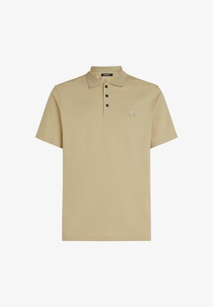 Beige polo särk pehmest kangast, millel on krae, lühikesed varrukad, kolm musta nööpi ja väike tikand rinnal.