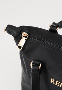 Borsa a spalla in nylon nero con zip e dettagli in tonalità oro. Presenta manici doppi e un logo sulla parte anteriore. Materiale testurizzato.