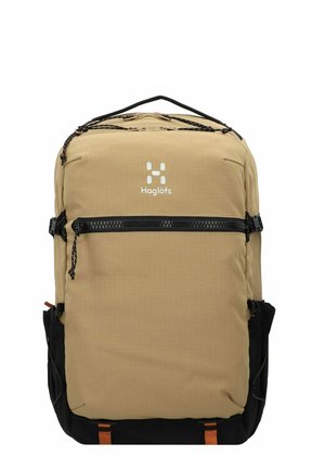 Mochila en tonos marrón y negro con un patrón de rejilla, bolsillo frontal con cremallera y correas ajustables. Presenta un logo y bolsillos de malla laterales.