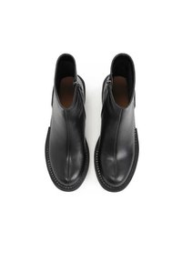Bottines en cuir noir avec une finition lisse, zip latéraux, bout arrondi et détail de semelle texturée, vues de dessus.