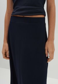 Jupe bleu marine, longueur cheville, en tissu doux. Comprend une taille lisse et un design fluide sans motifs ni embellissements visibles.