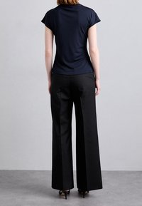 Navy topp med kort ärm och svarta vida byxor. Toppen har ett slätt tyg; byxorna har en skräddarsydd design med en subtil lyster.