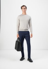 Suéter de color beige claro, pantalones azul marino, zapatos negros y un bolso tote de cuero negro. Diseño sencillo con una textura suave.
