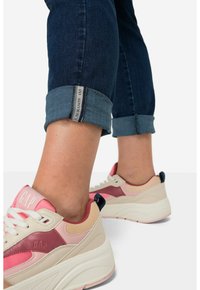 Tenisky s kombinací růžových, béžových a mahagonových materiálů. Zaoblená špička, texturovaná síťovina a vrstvený design s robustní podrážkou. Džínové kalhoty na nohavicích ohrnuté.