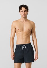Črne kopalne kratke hlače z vrvico v pasu, s gladko teksturo in preprosto zasnovo. Brez vzorcev ali poudarkov.