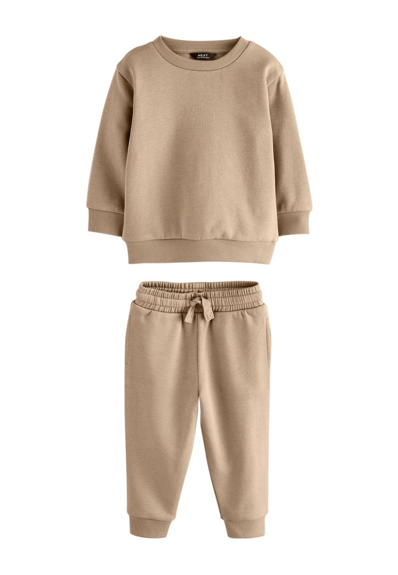 Bluza bej din bumbac cu guler rotund și manșete striate, asortată cu pantaloni de trening cu talie elastică și glezne tivite.